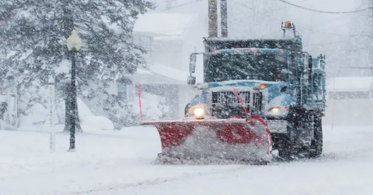 a large SUV drives on an icy road flanked by fir trees