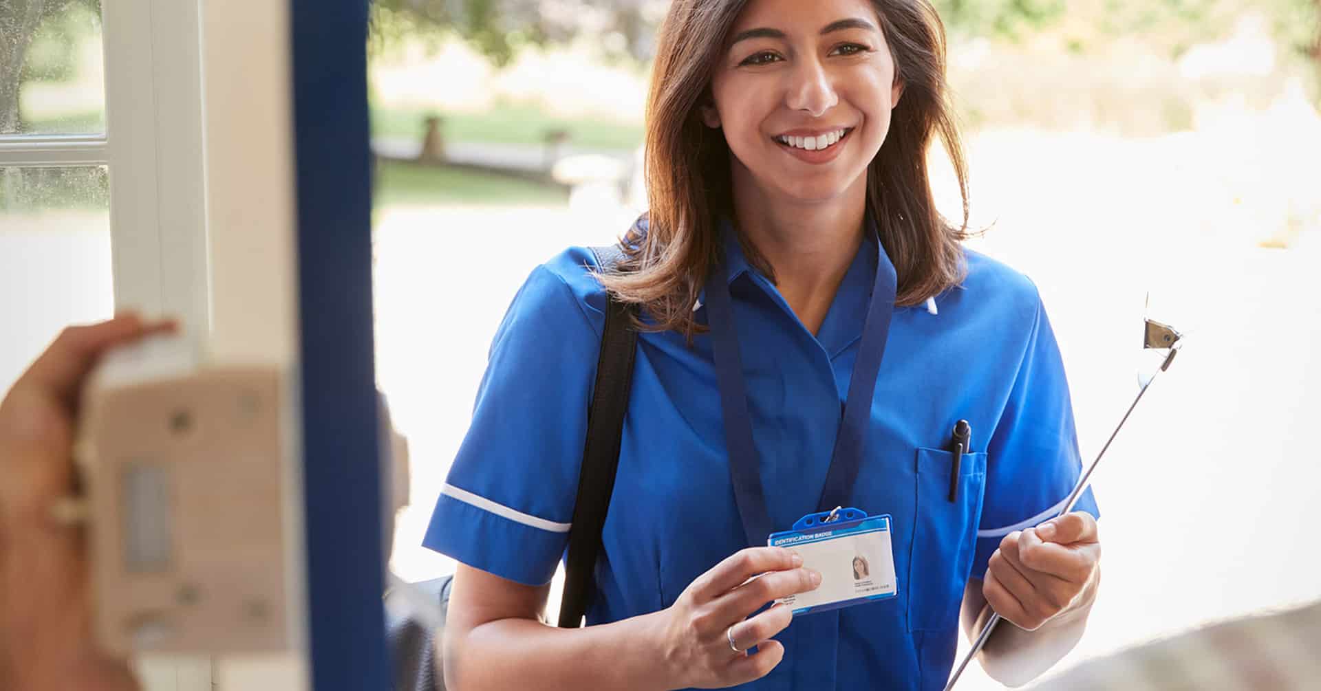 a home health care nurse greets her patient as she enters the patient's home