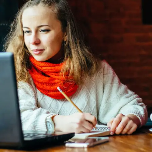 woman in red scarf looking at laptop computer