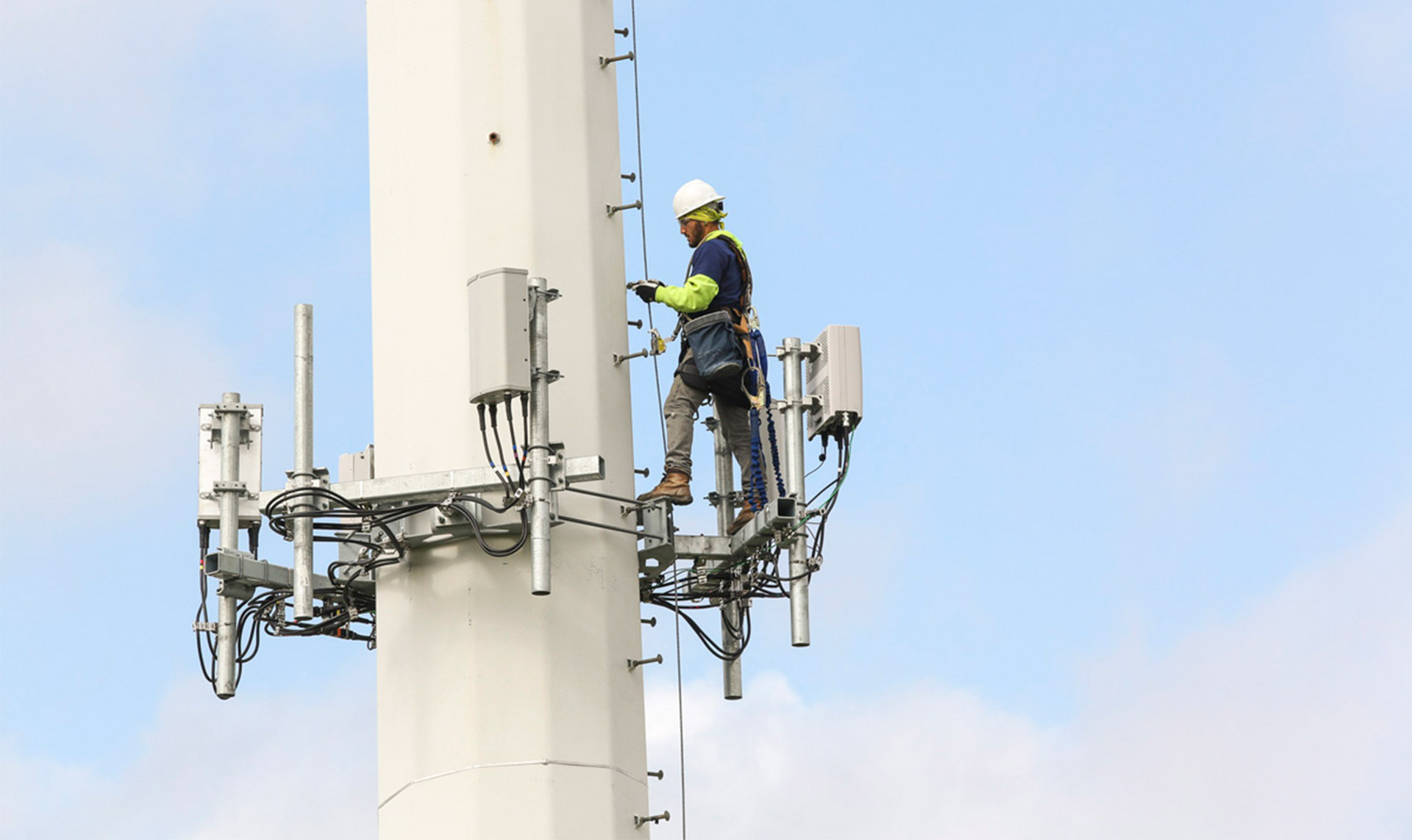 worker in hardhat working on cell tower