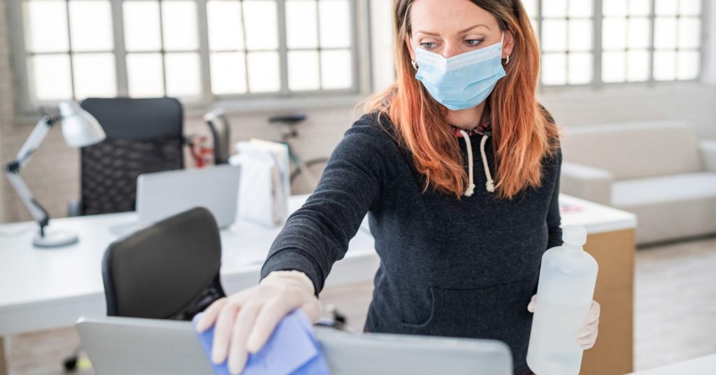 woman wearing mask cleaning office