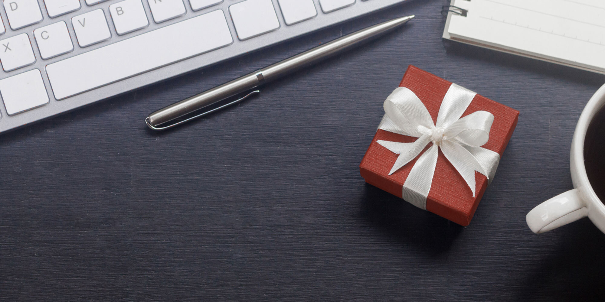 red gift box with white bow sitting on black desk