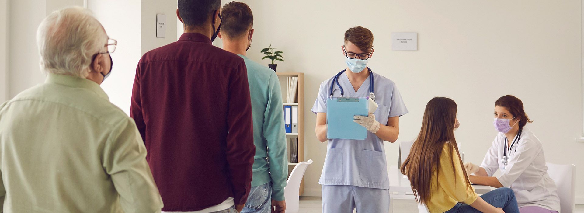 people in line at a medical facility with two medical staff offering service