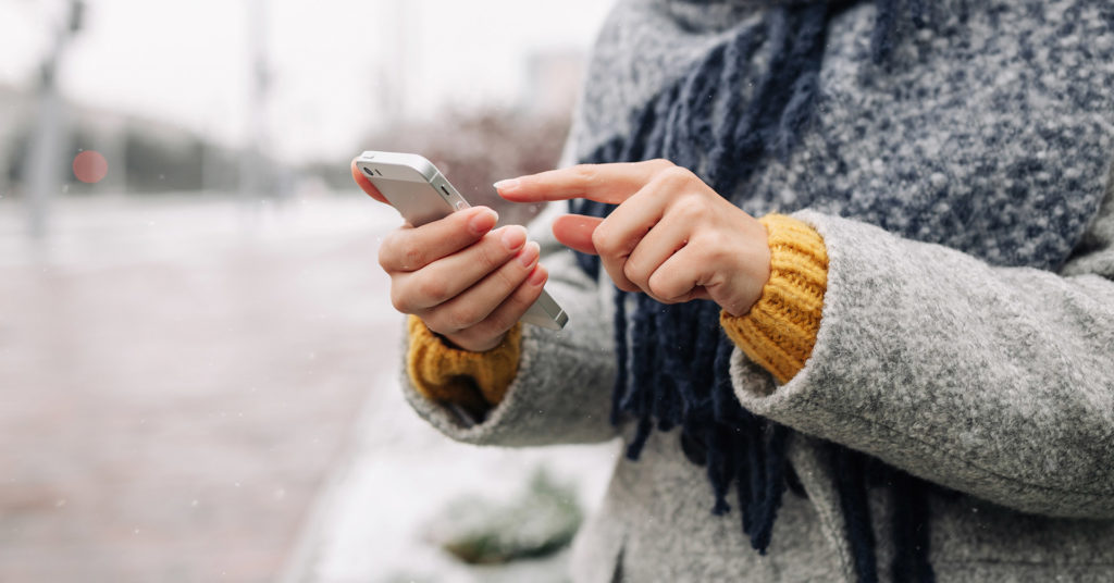 Remote employee checking phone outdoors in winter weather