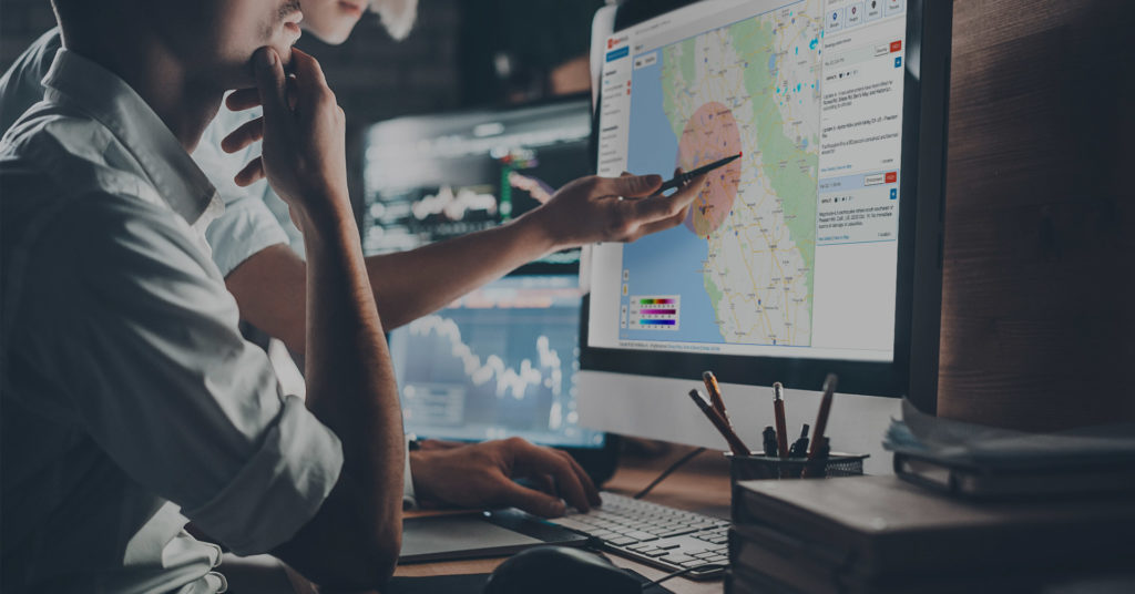 Man at computer monitor showing AlertMedia threat intelligence map