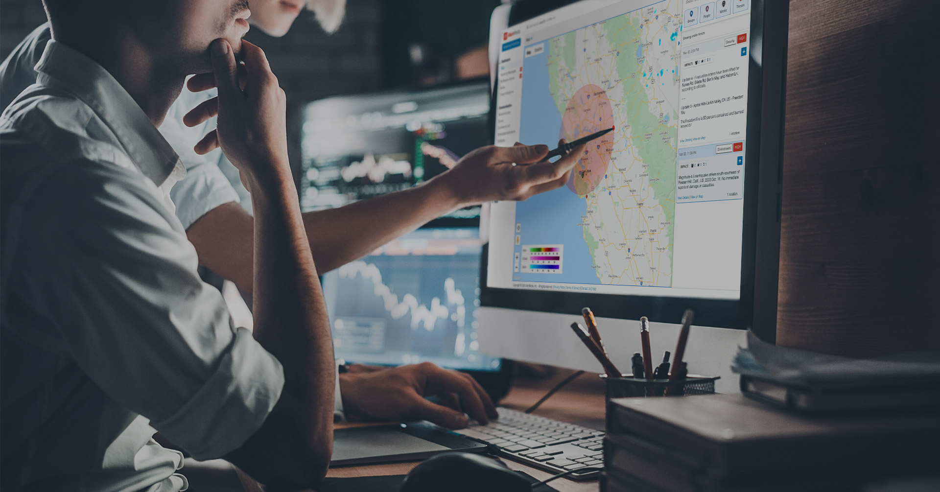 Man at computer monitor showing AlertMedia threat intelligence map