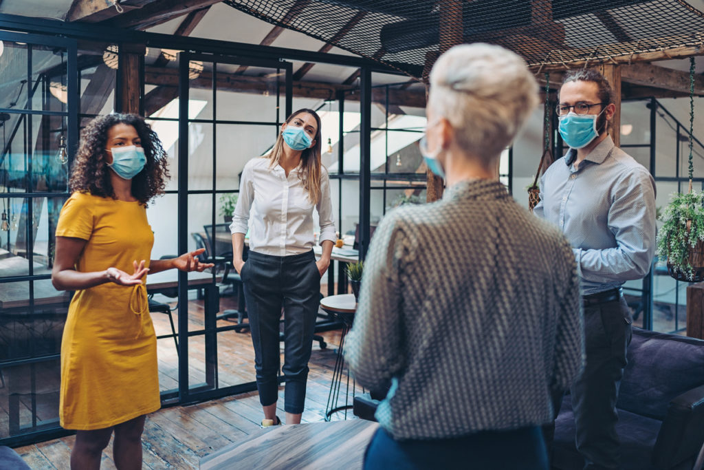 Group of employees wearing masks and standing at a distance in an office