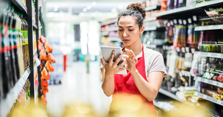 Retail employee in aisle using tablet