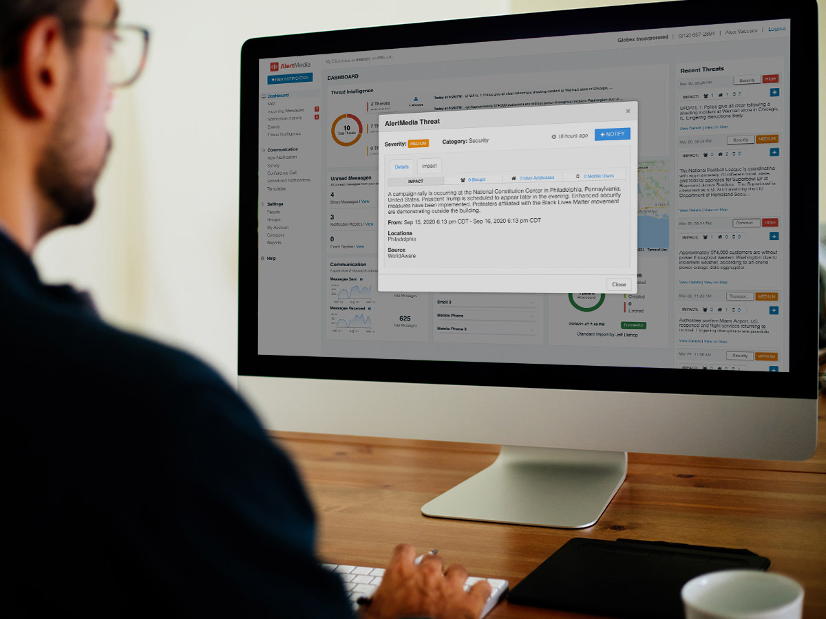 man with glasses looking at desktop computer with threat notification on screen