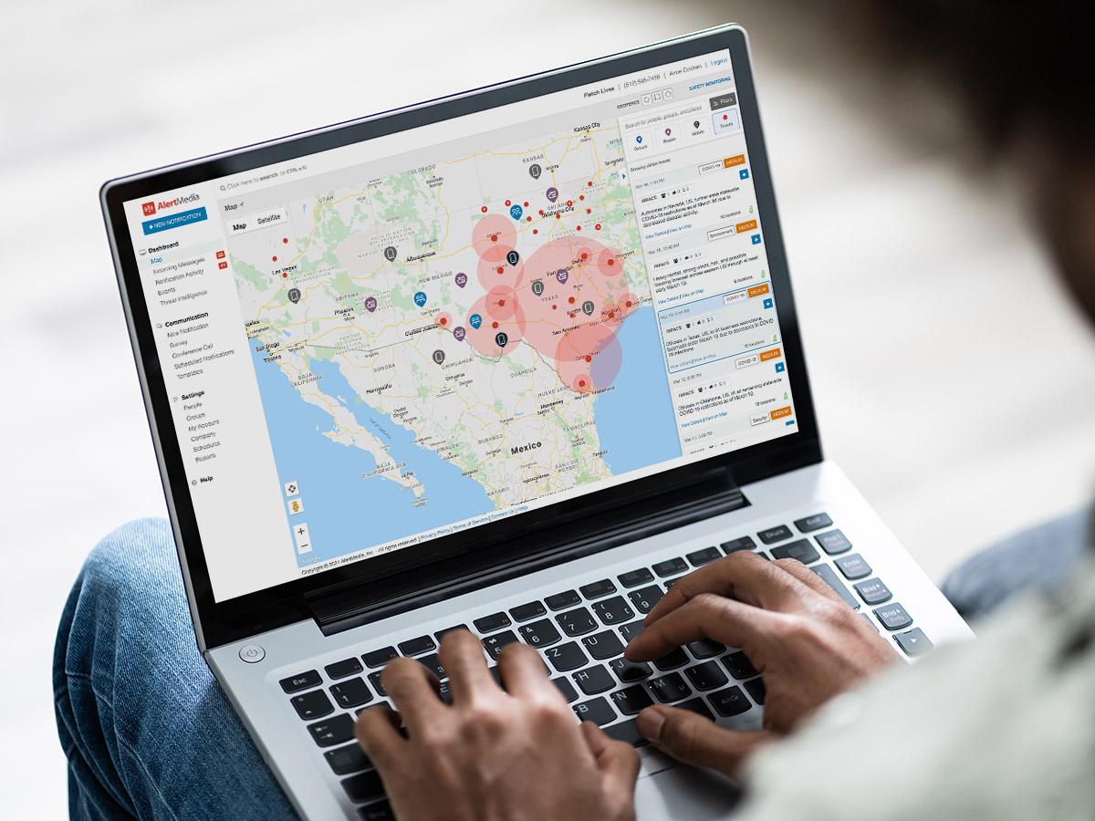 laptop sitting on person's legs with a map showing threat data on screen