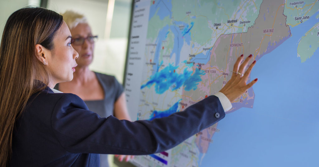 two women inspecting a large digital threat map