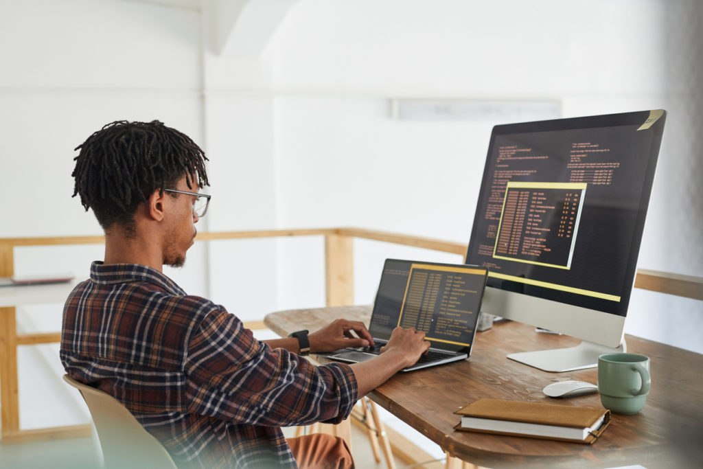 African-American IT developer typing code on a computer.