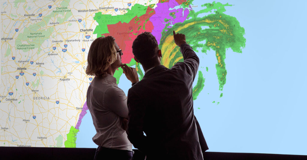 two men look at a map of a hurricane about to make landfall in North Carolina