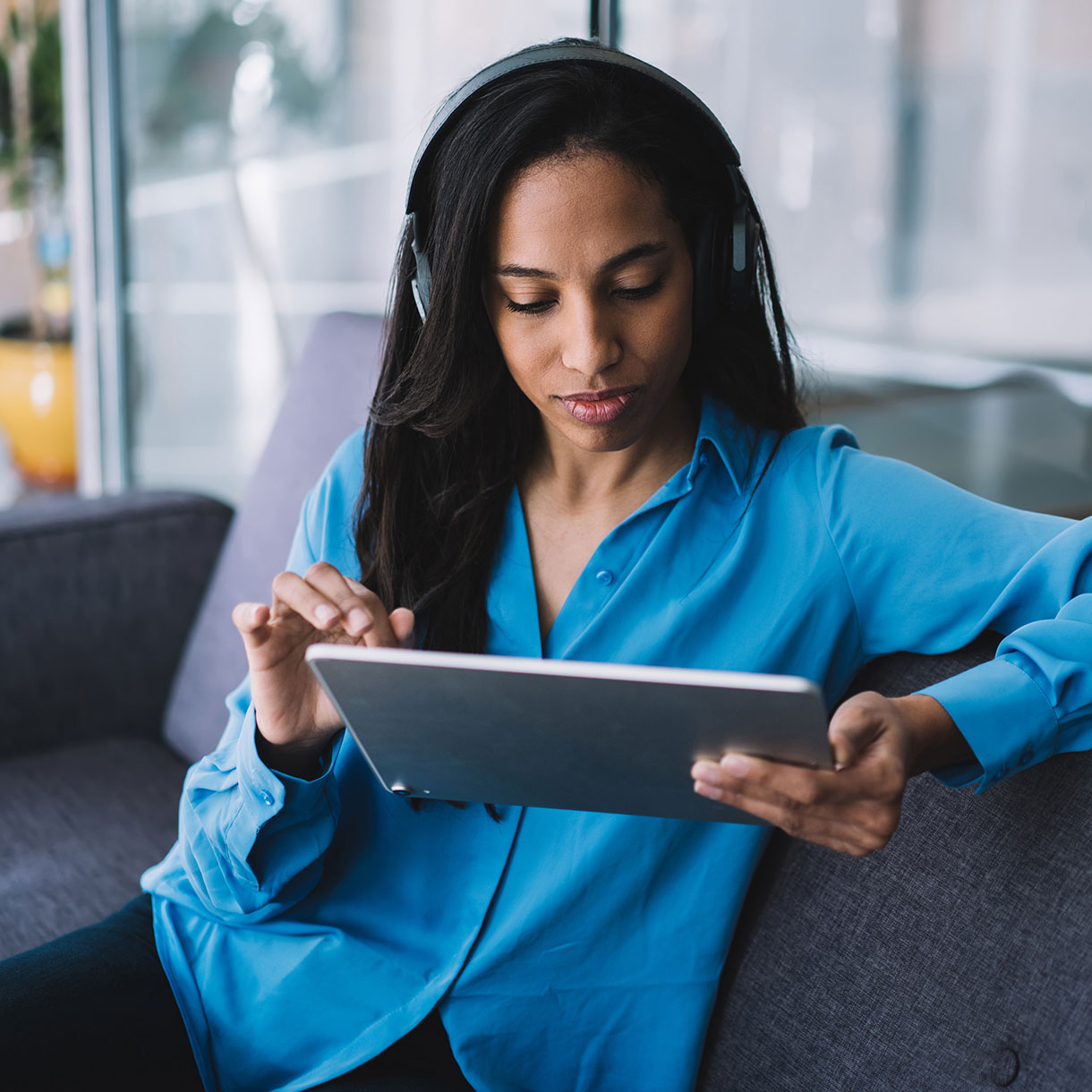 woman in blue blouse using a handheld tablet device
