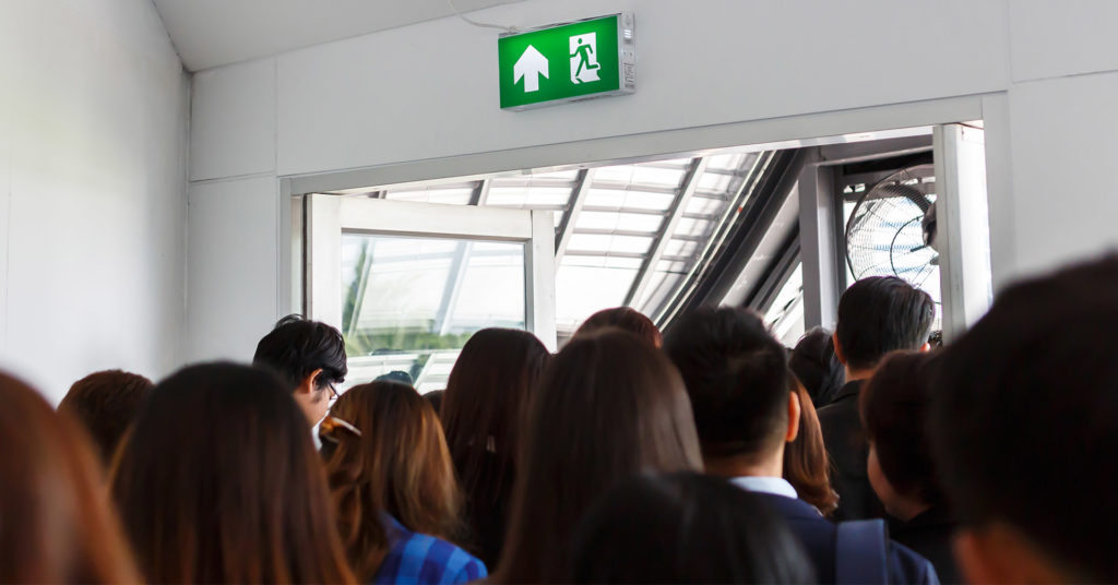 Group of employees approaching doorway under exit sign leaving building