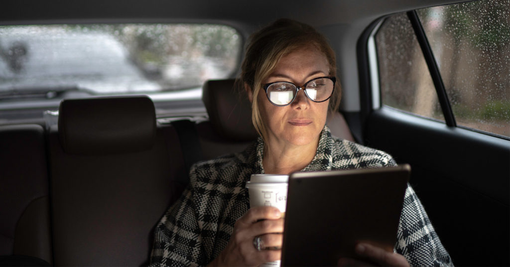 Remote worker in vehicle reading on tablet device