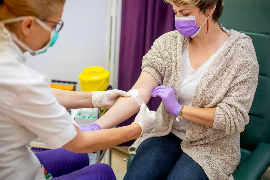 Applying adhesive bandage after taking sample for blood test