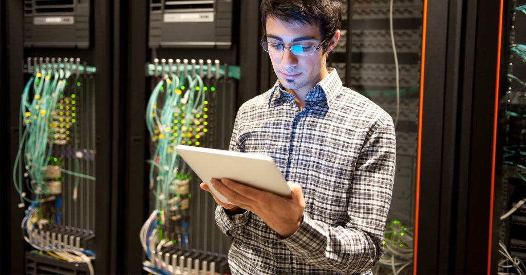 man looking at tablet in front of servers