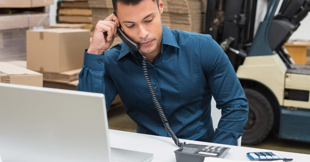 Man talking on landline phone while at desk