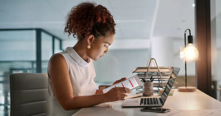 Woman at desk reading message on tablet