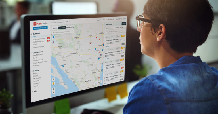 Person with short hair and glasses looking at desktop screen showing threat history map
