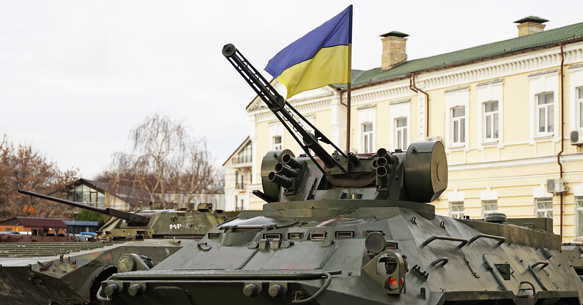 Military vehicle in foreground with Ukraine flag behind