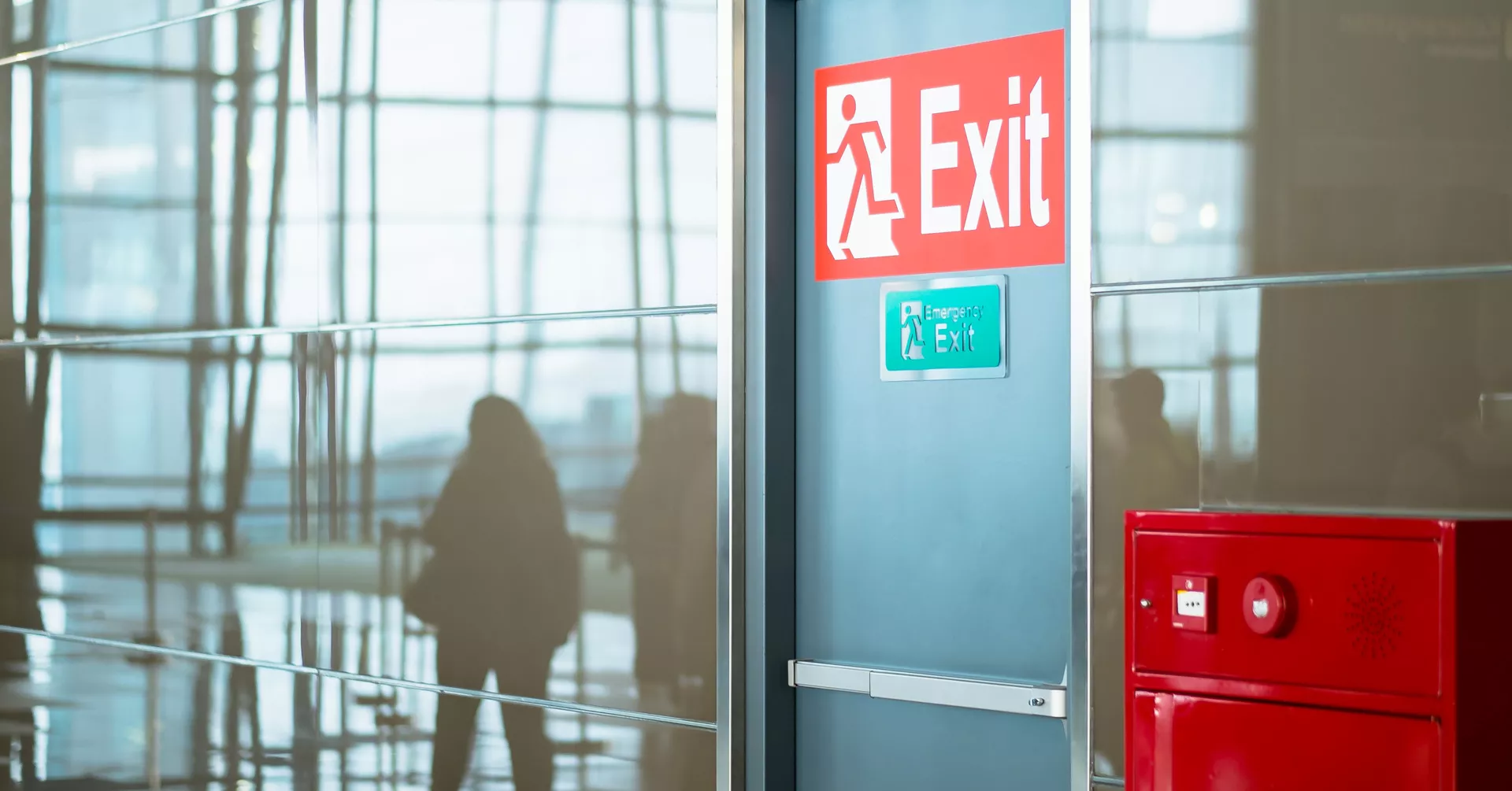 red "exit" sign on wall next to fire alarm panel