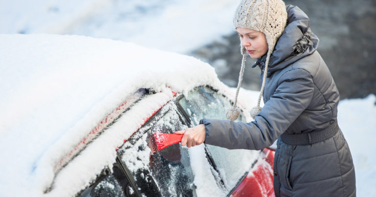 person scrapes ice off car windshield