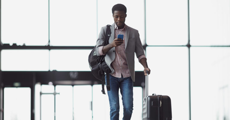 A business traveler navigates through the airport, checking for mobile updates.