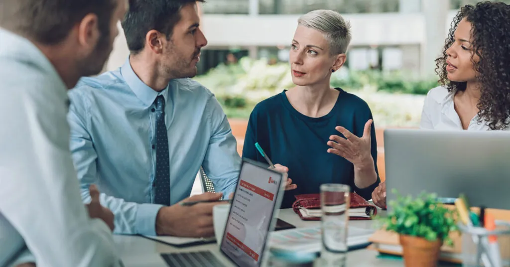 Stakeholders have a discussion at a conference table, compiling an after-action report.