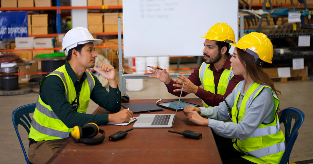 Workers in vests and hard hats perform an after action review.