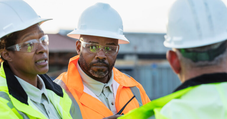 Workers in safety gear have a discussion