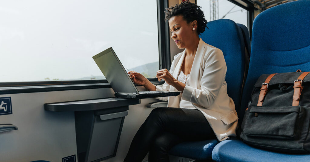 Seated smiling worker uses laptop on train