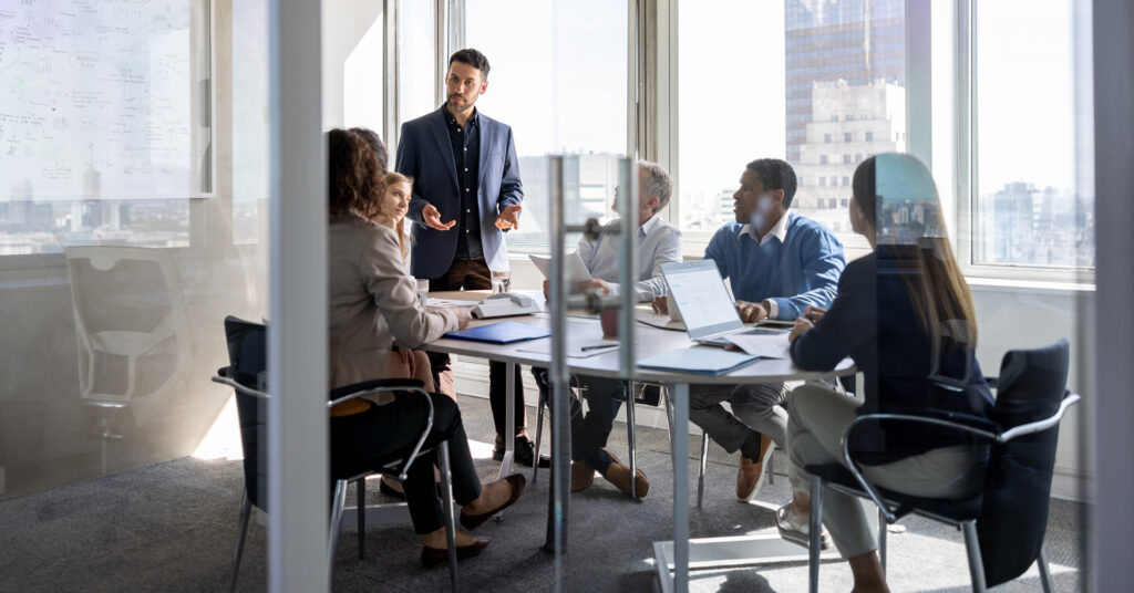 Stakeholders gather around a conference table to discuss business threats and plans.