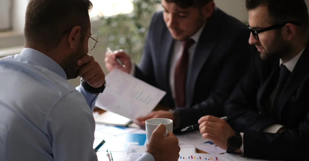 Three people sit together at a table to discuss operational risks to their business