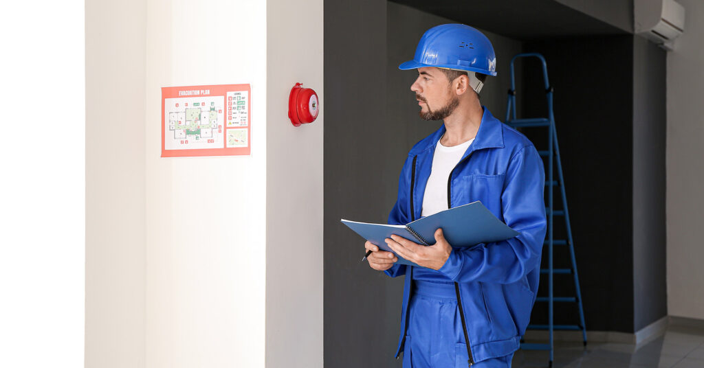 A man inspects a fire alarm, preparing for a fire emergency response.