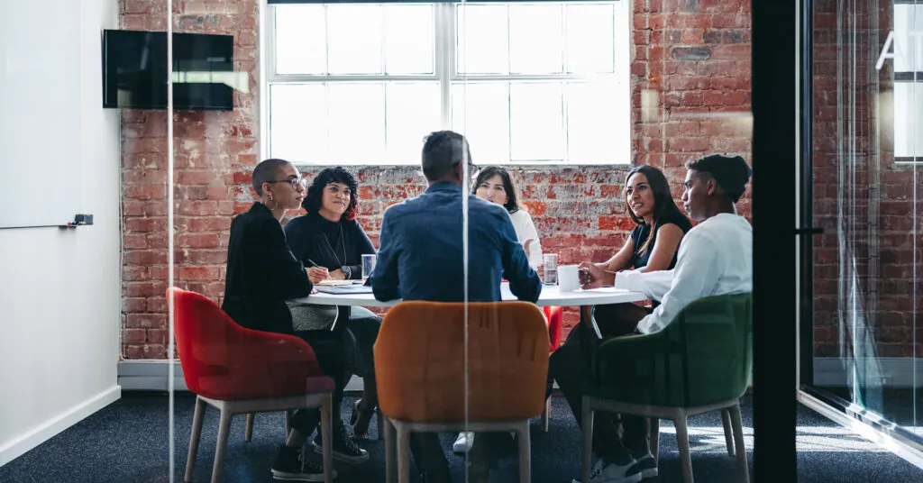 Six co-workers sit around a conference table for a safety meeting