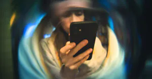 A person holds their phone, looking at the screen, and there is a distortion field surrounding them